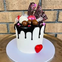 White chocolate drip cake loaded with Maltesers, chocolate bars, sprinkles and a red heart
